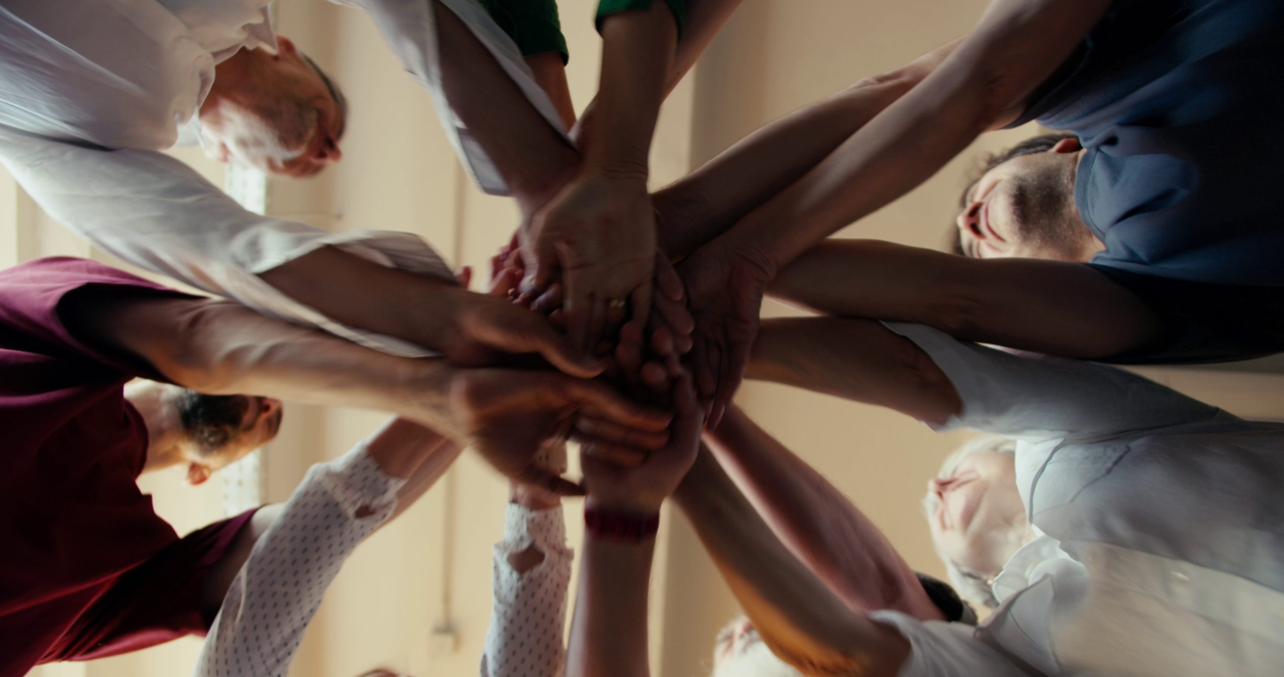 Group of people joining hands together in teamwork and support.