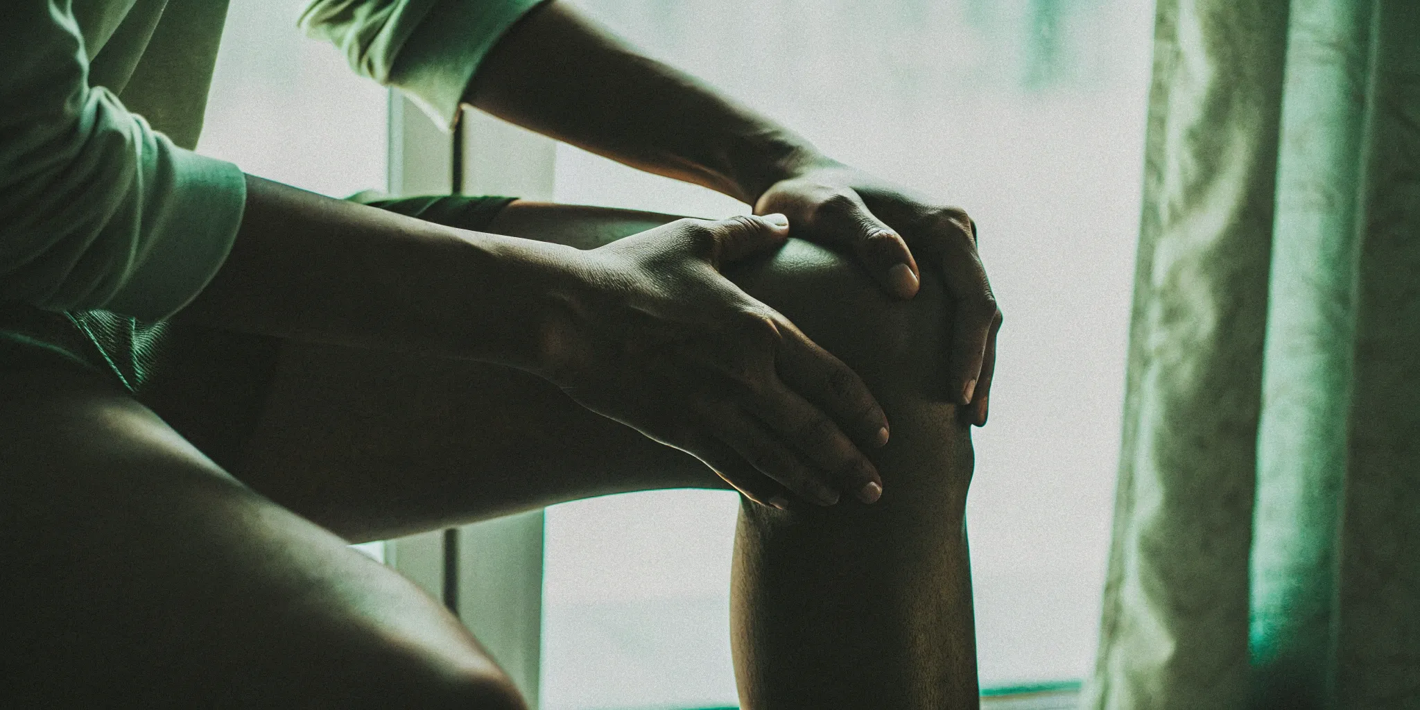 Person holding their knee in pain, considering the cost of stem cell injections.